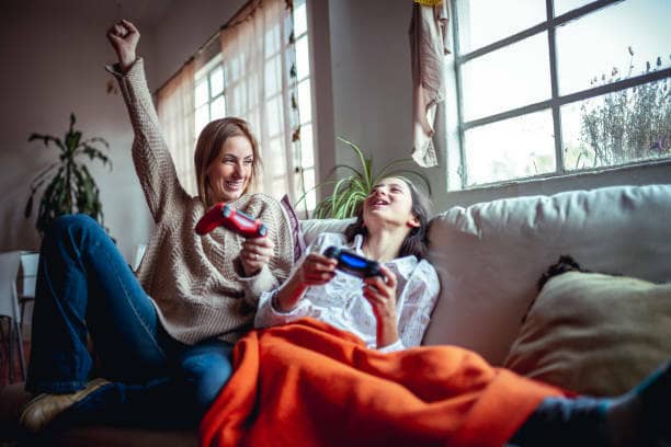 Mother and daughter enjoying video games together as affordable ways to spoil your mum at home