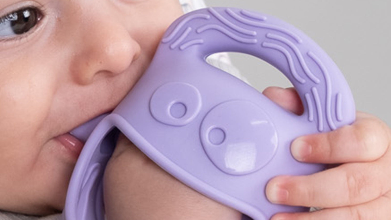 Baby holding a purple teething toy with 'Mochi' branding.