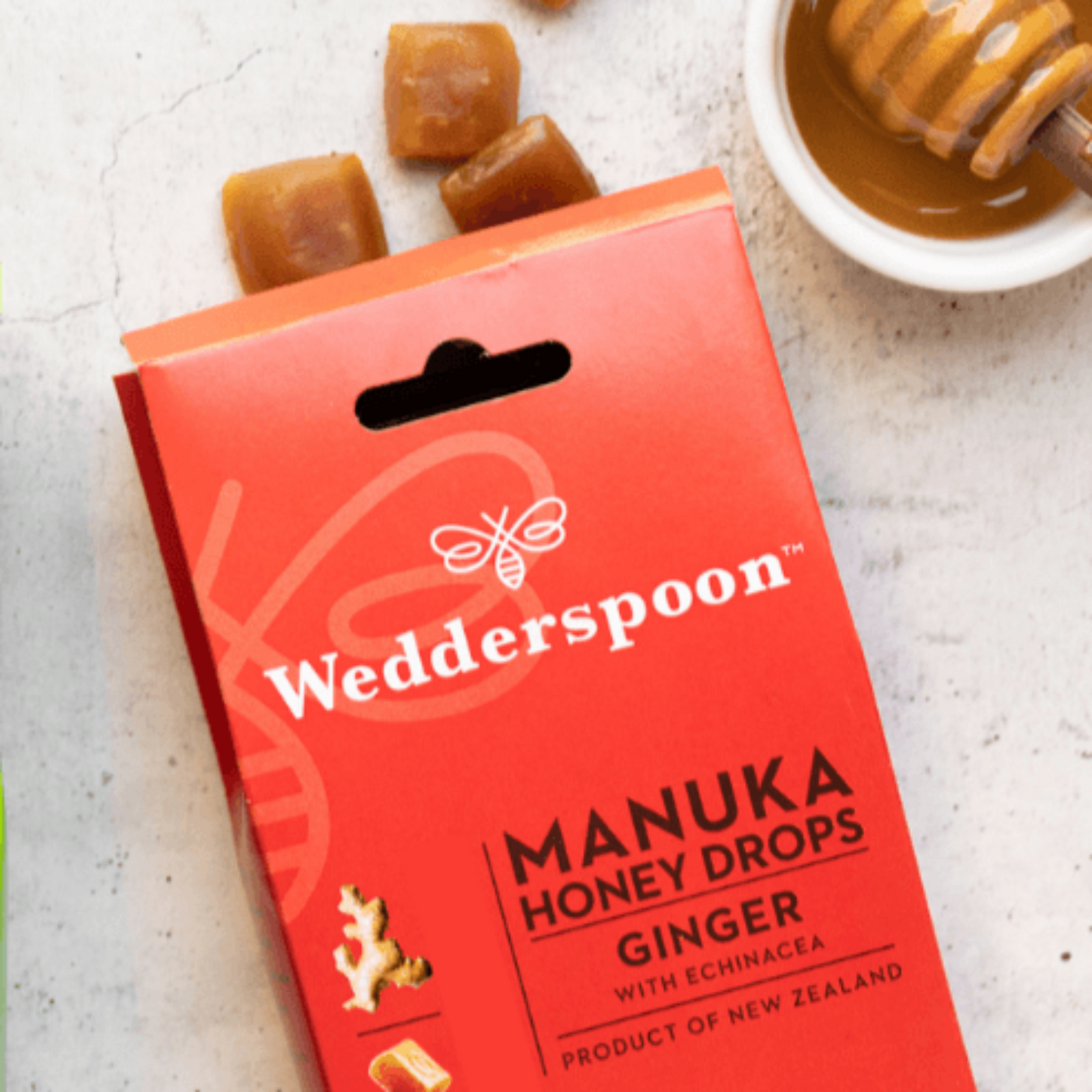 Yellow package of Wedderspoon Manuka Honey Drops Ginger on a light background