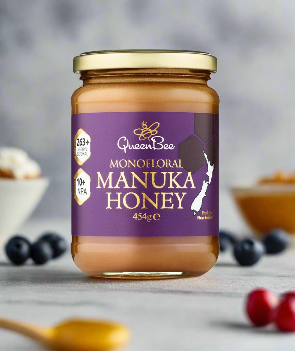 QueenBee manuka honey 454g glass jar with purple label and gold lid on blurred background