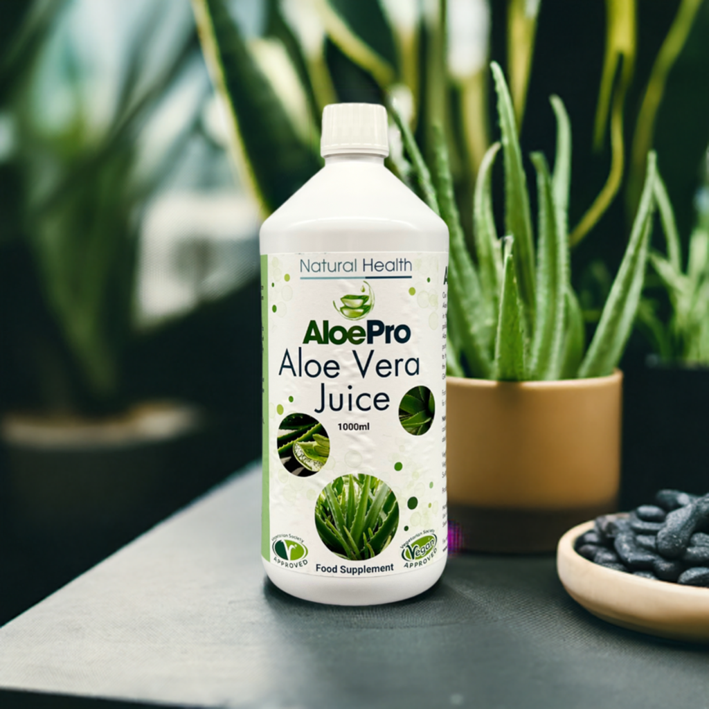 AloePro Aloe Vera Juice 1000ml bottle by Natural Health World UK on table with potted aloe plants