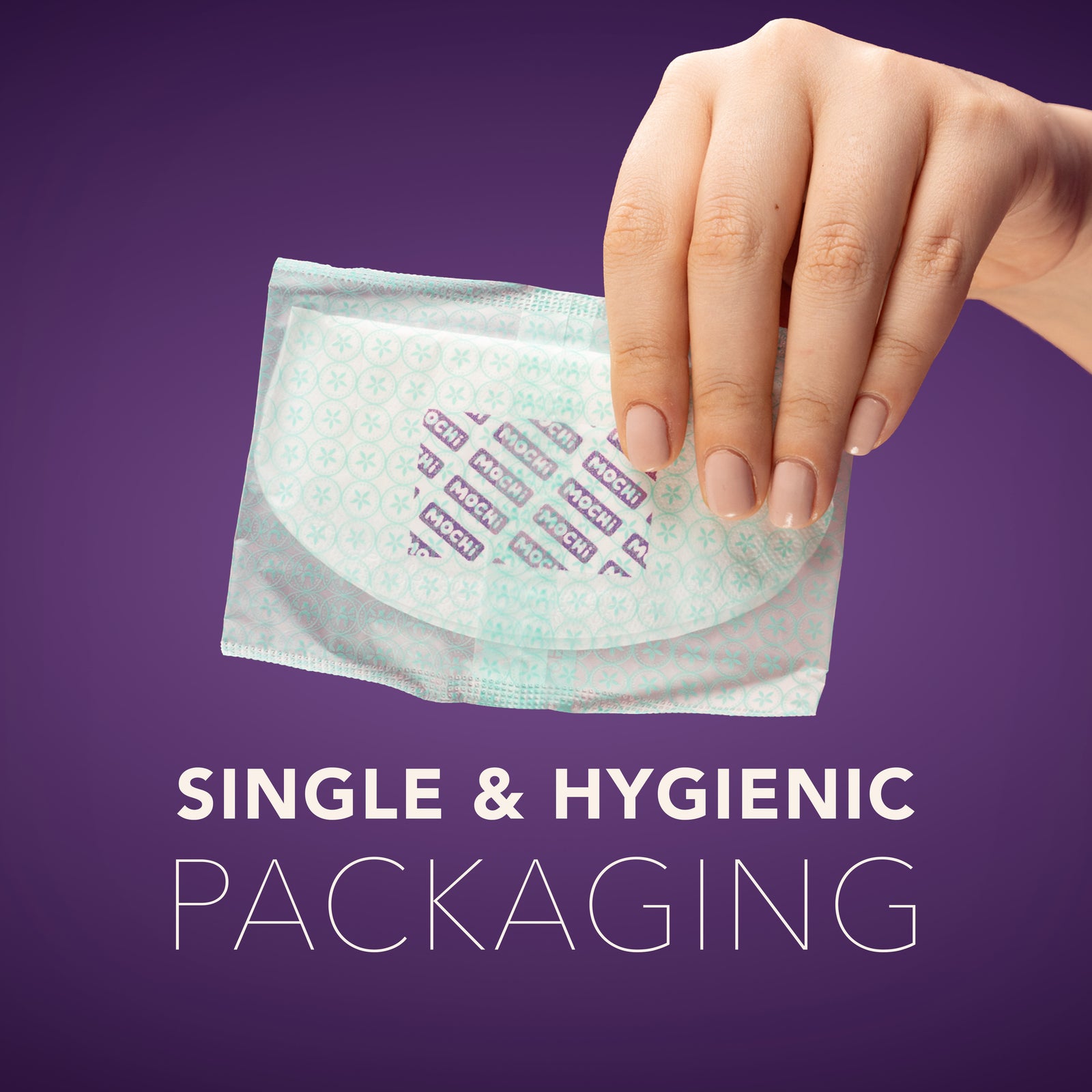 Hand holding single hygienic pack of MOCHi breast pads for breastfeeding on purple background