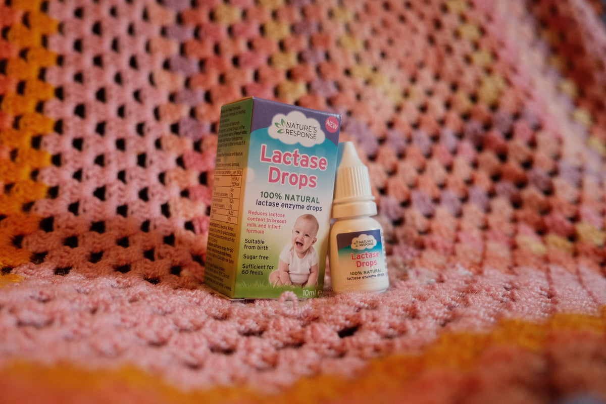 Natures Response Lactase Drops box and bottle on pink knitted blanket showing natural lactase drops for babies