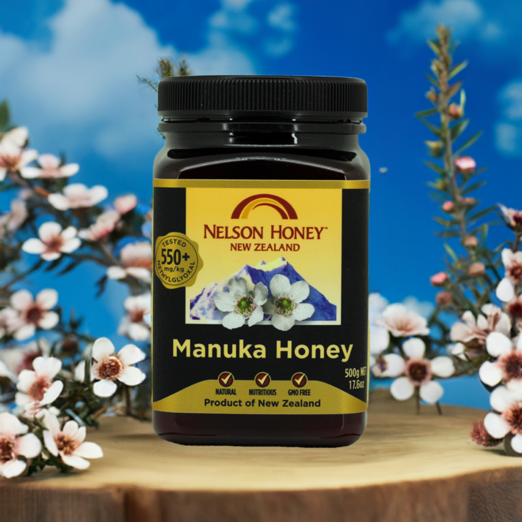 Nelson Honey Manuka honey MGO 550 plus 500g jar on wooden stump with manuka flowers backdrop
