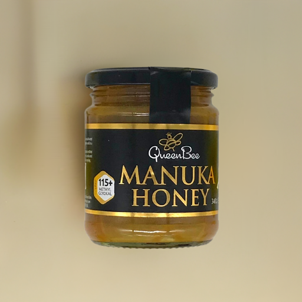 Queen Bee Manuka honey MG115 in a glass jar with black and gold label showing 115 plus methylglyoxal content