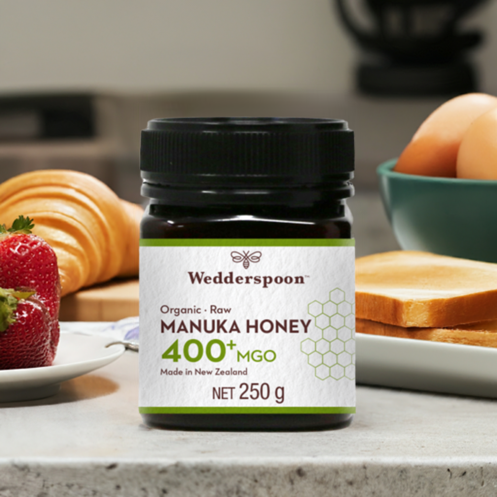 Wedderspoon high potency raw manuka honey 400 MGO jar 250g on kitchen counter with breakfast items