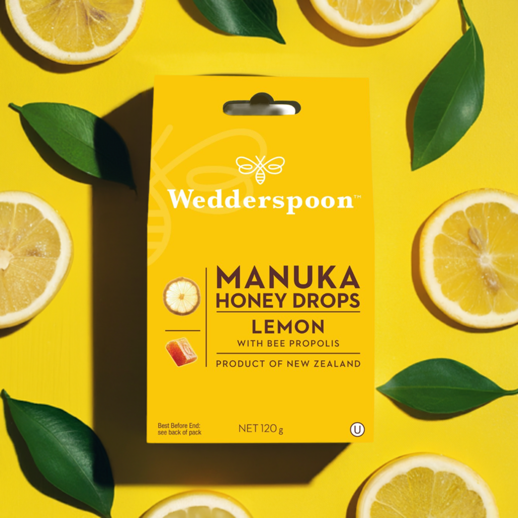 Wedderspoon Manuka honey drops lemon box with lemon slices and green leaves on yellow background