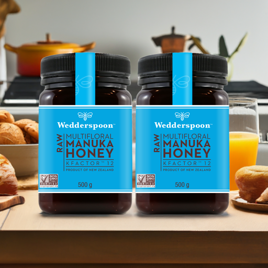 Two jars of Wedderspoon KFactor 12 honey raw multifloral Manuka honey 500 gram jars on kitchen counter