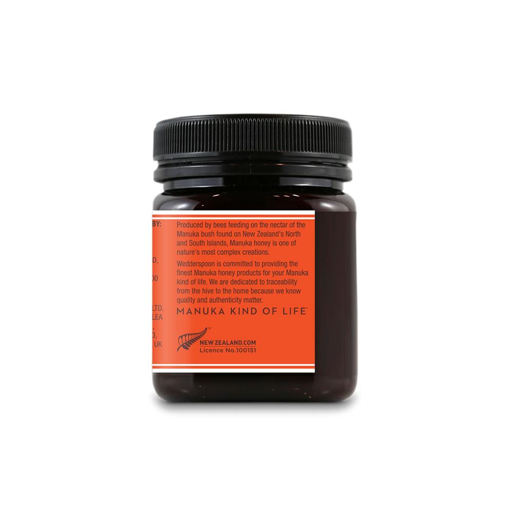 Wedderspoon raw Manuka honey KFactor 16+ dark glass jar with black lid showing orange label rear view